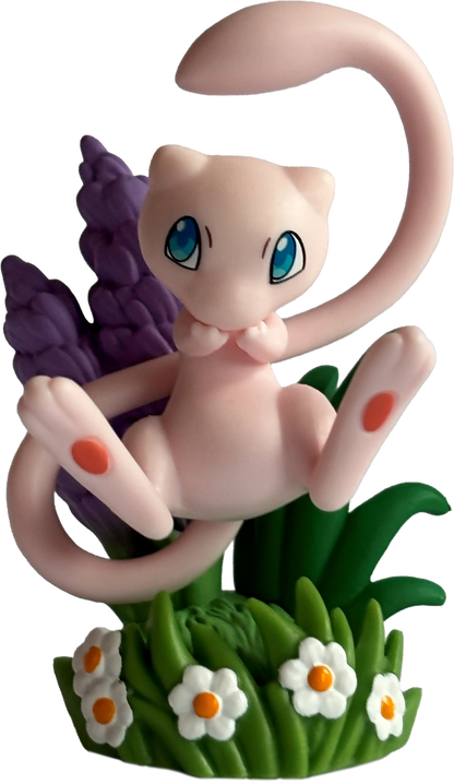 Pokémon Mew-Figur auf grünem Gras mit Blumen und ausgestrecktem Schwänzchen